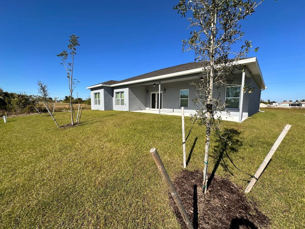 A modern two-story house with a flat roof, large windows, and a well-maintained lawn.