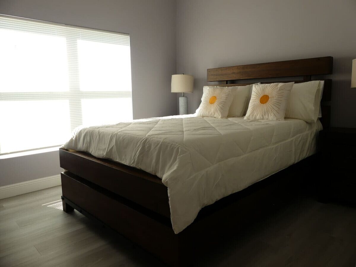 A bedroom with a bed, a nightstand, and a lamp.