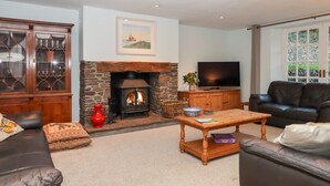 A living room with a stone fireplace, a television, a sofa, and a cabinet. - Trentishoe Coombe (Barnstaple)