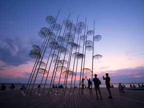 A pier with people sitting and walking, and a unique installation of transparent umbrellas. - Sanders Tower Centre - Homey 1-bdr Apt w/ Terrace (Thessaloniki)