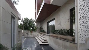 Edifici modern amb sòl mullat, escales cap a una porta i plantes en testos.