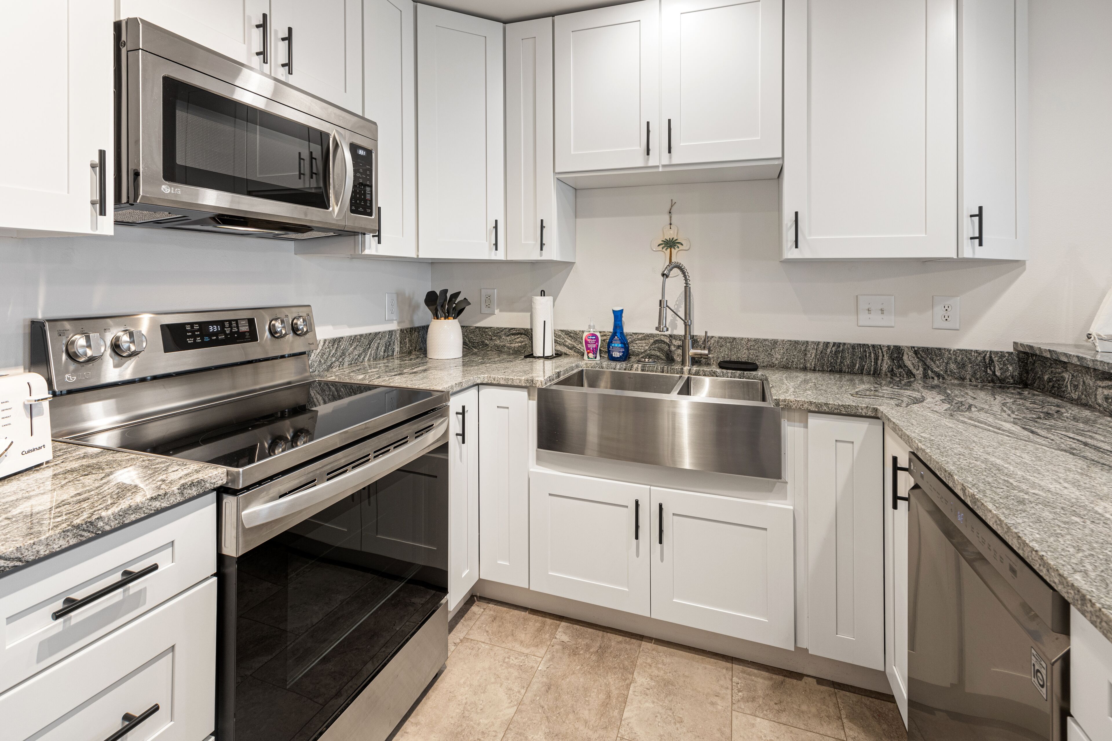 A modern kitchen with white cabinets, stainless steel appliances, and granite countertops.