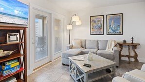 Ein Wohnzimmer mit grauem Sofa, Couchtisch und Bücherregal mit Gesellschaftsspielen.