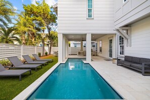 A modern house with a swimming pool, outdoor seating, and a covered patio area.