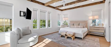 A bedroom with a bed, a sofa, a nightstand, and a window with blinds.