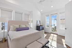 Een slaapkamer met een groot bed, een plafondventilator en uitzicht op buiten.