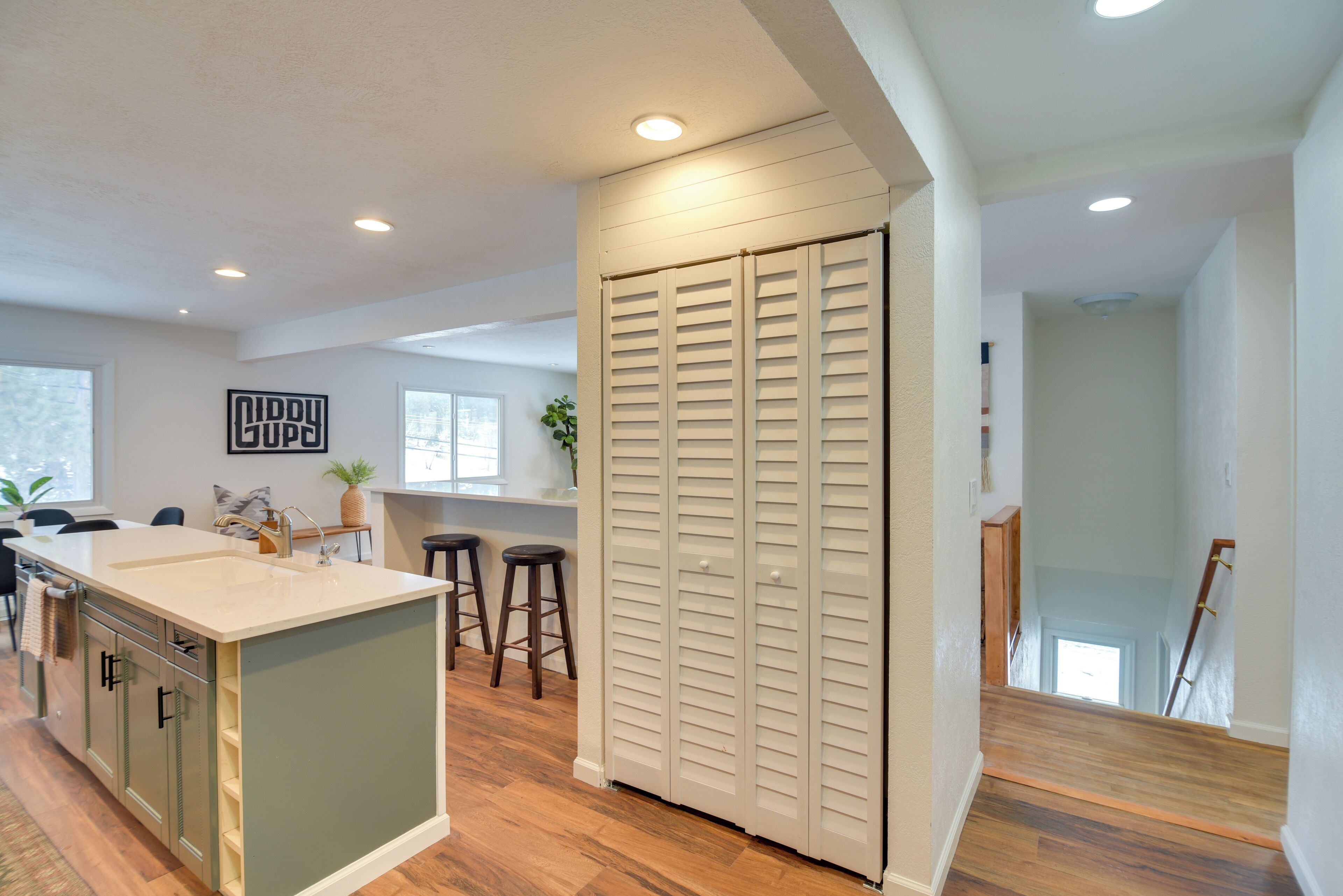 A kitchen with a central island, wooden flooring, and a white ceiling with recessed lighting.