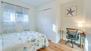Un dormitorio con cama, escritorio con silla, ventana con cortinas y una decoración de estrella de mar en la pared.