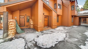 Ett tvåvåningshus i trä med en inglasad veranda, en hög med ved och en snötäckt uppfart.