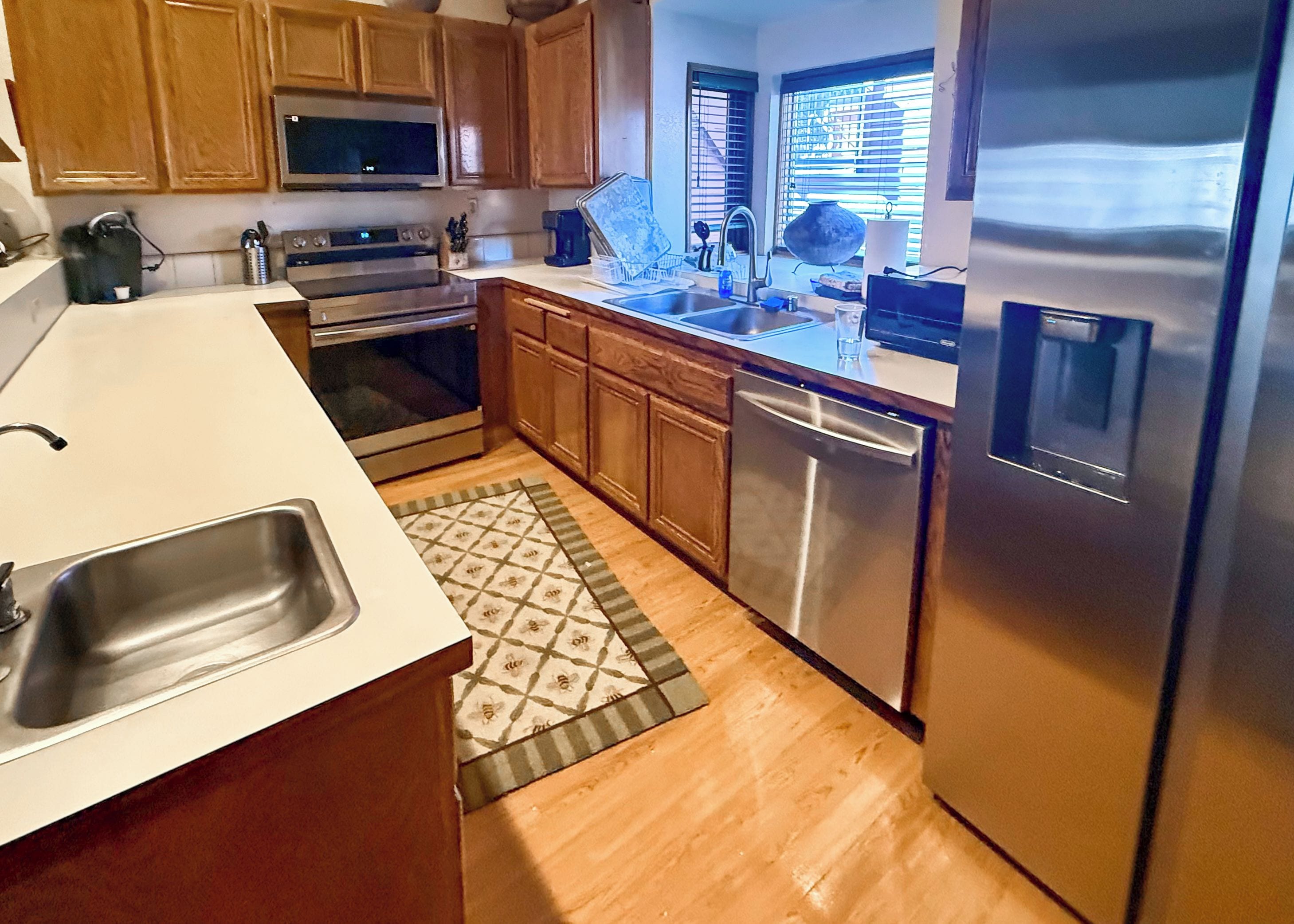 A kitchen with wooden cabinets, stainless steel appliances, and a patterned rug.