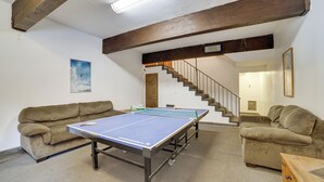 A room with a ping pong table, two sofas, a wooden table, and a staircase. - Mammoth Lakes Condo: Walk to Village & Gondola! (Mammoth Lakes)