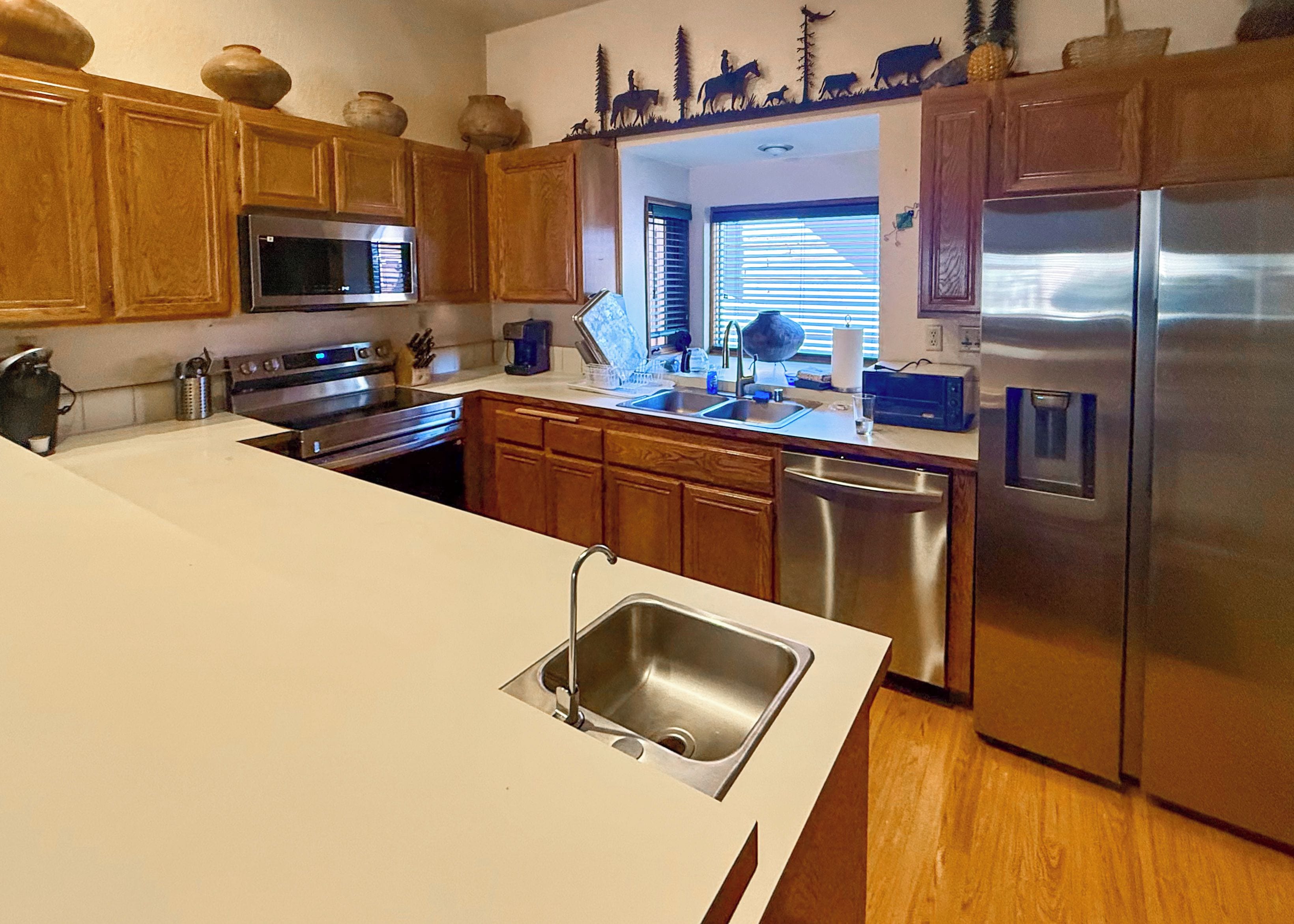 A kitchen with wooden cabinets, stainless steel appliances, and a white countertop.
