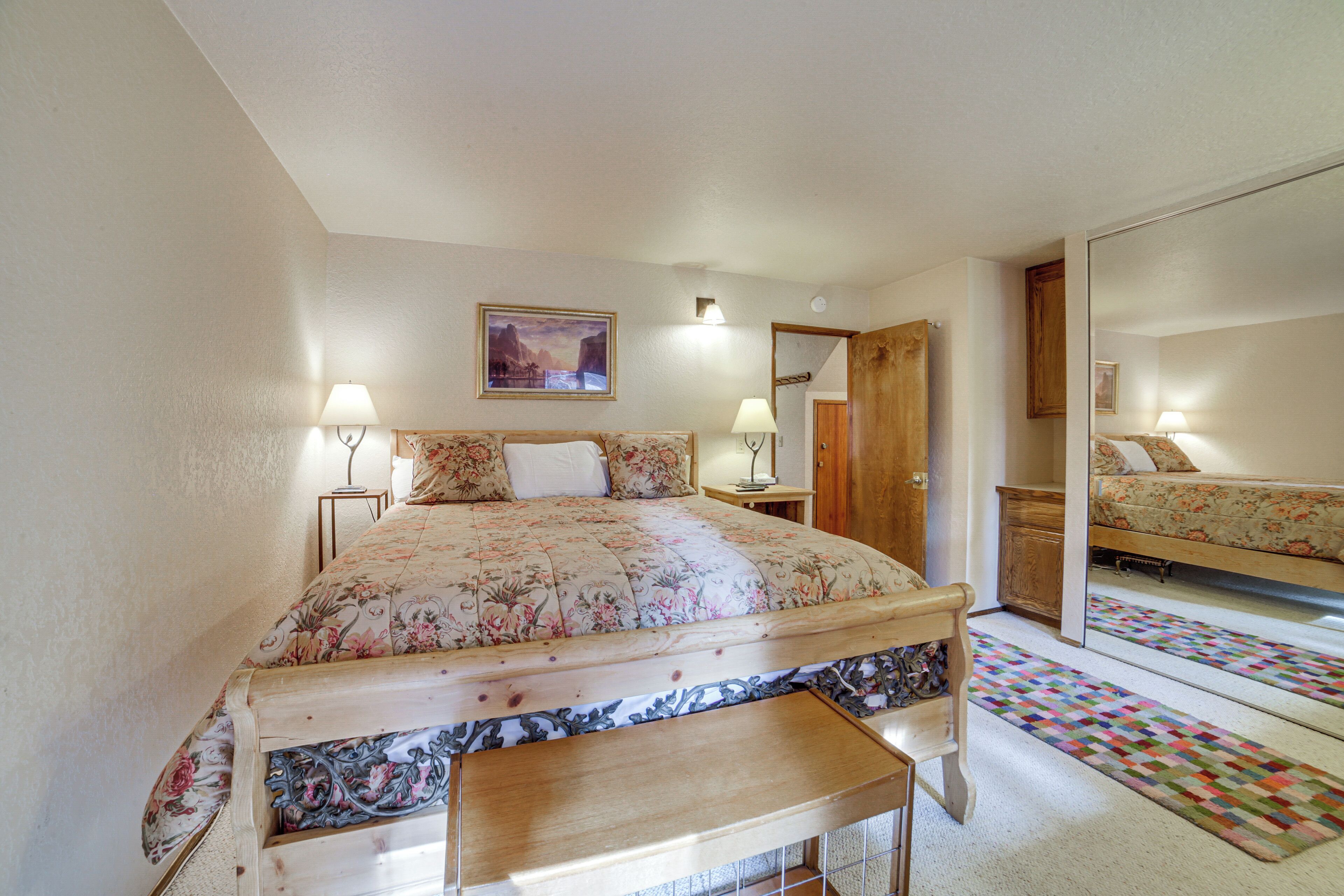A bedroom with a bed, bedside tables, a mirror, and a door.