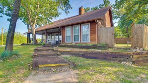 A rustic wooden house with a porch, large windows, and a covered outdoor area.