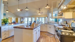 A spacious kitchen with a central island, white cabinetry, and a large stove.