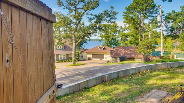 A residential street with houses, a wooden fence, and trees.