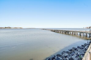 A calm waterfront with a wooden pier extending into the water. - Coastal Virginia Home w/ Private Beach Access! (Colonial Beach)