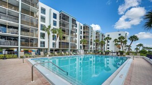 A modern hotel with a swimming pool, multiple balconies, and palm trees. - Marco Island Waterfront Condo w/ Community Pool! (Marco Island)