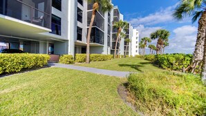 A modern building with multiple balconies, palm trees, and well-maintained lawns. - Marco Island Waterfront Condo w/ Community Pool! (Marco Island)