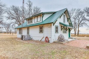 A single-story house with a green roof and white siding, a brick driveway, and a small front yard. - Comanche County Home Near Hunting & Fishing! (Protection)