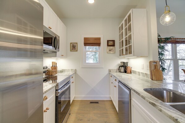 A kitchen with white cabinets, stainless steel appliances, a window with blinds, and a hanging light fixture. - Charming Appomattox Home: Half-mi to Main Street! (Appomattox)