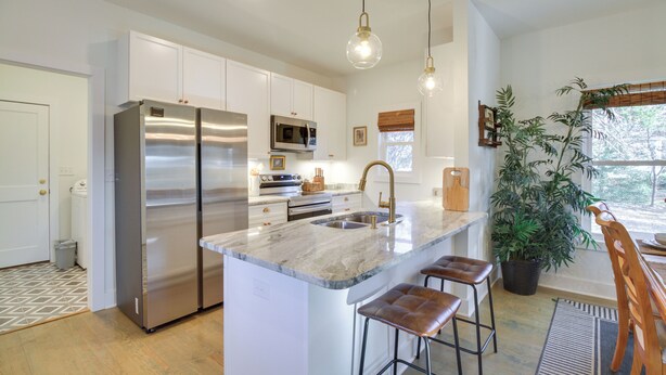 A modern kitchen with stainless steel appliances, a marble island, and bar stools. - Charming Appomattox Home: Half-mi to Main Street! (Appomattox)