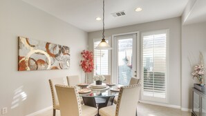 A dining area with a glass table, four chairs, a hanging light fixture, and a painting on the wall. - 2 Mi to Empire Polo Club: Indio Home w/ Fireplace! (Indio)