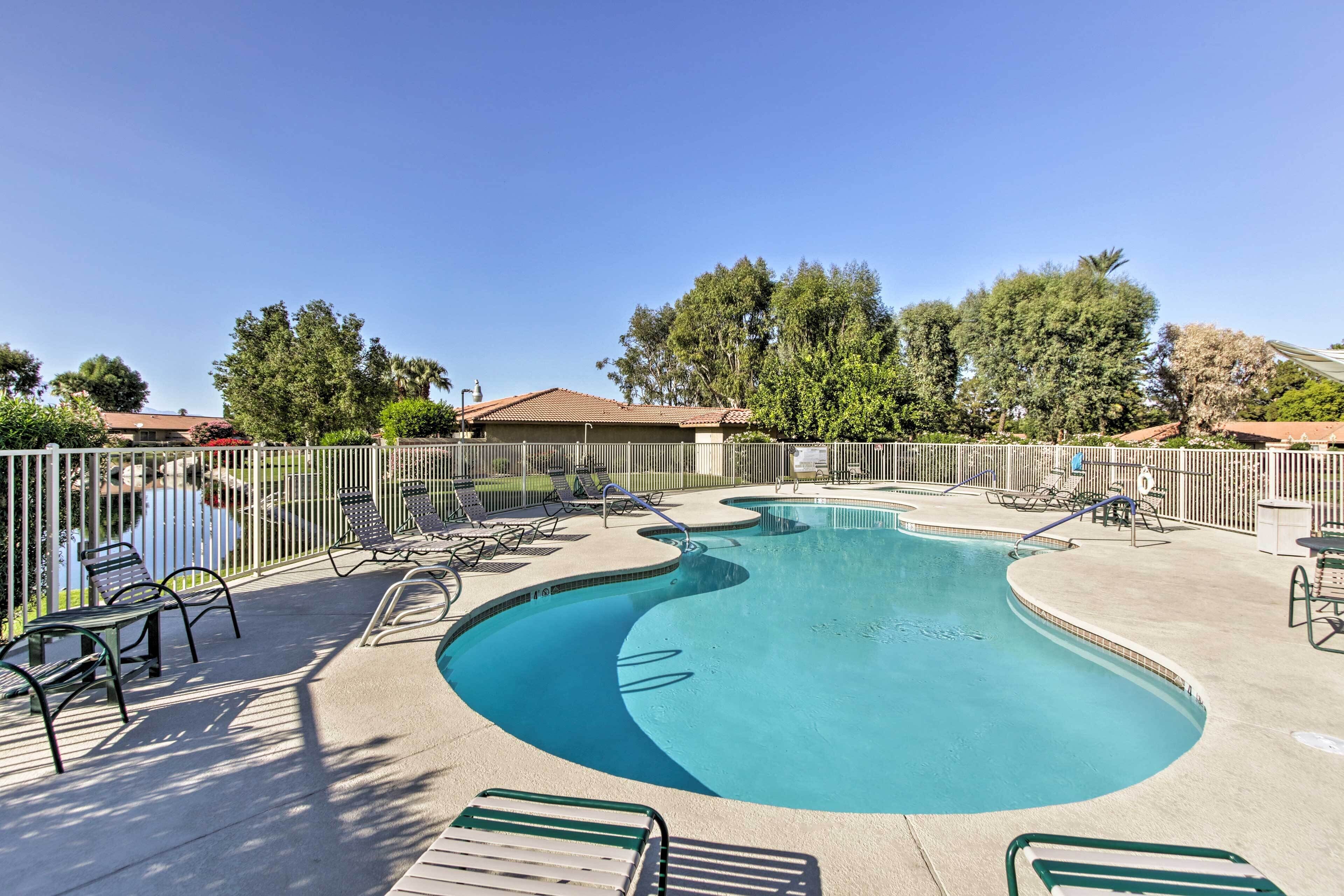 A swimming pool with lounge chairs and a fence.