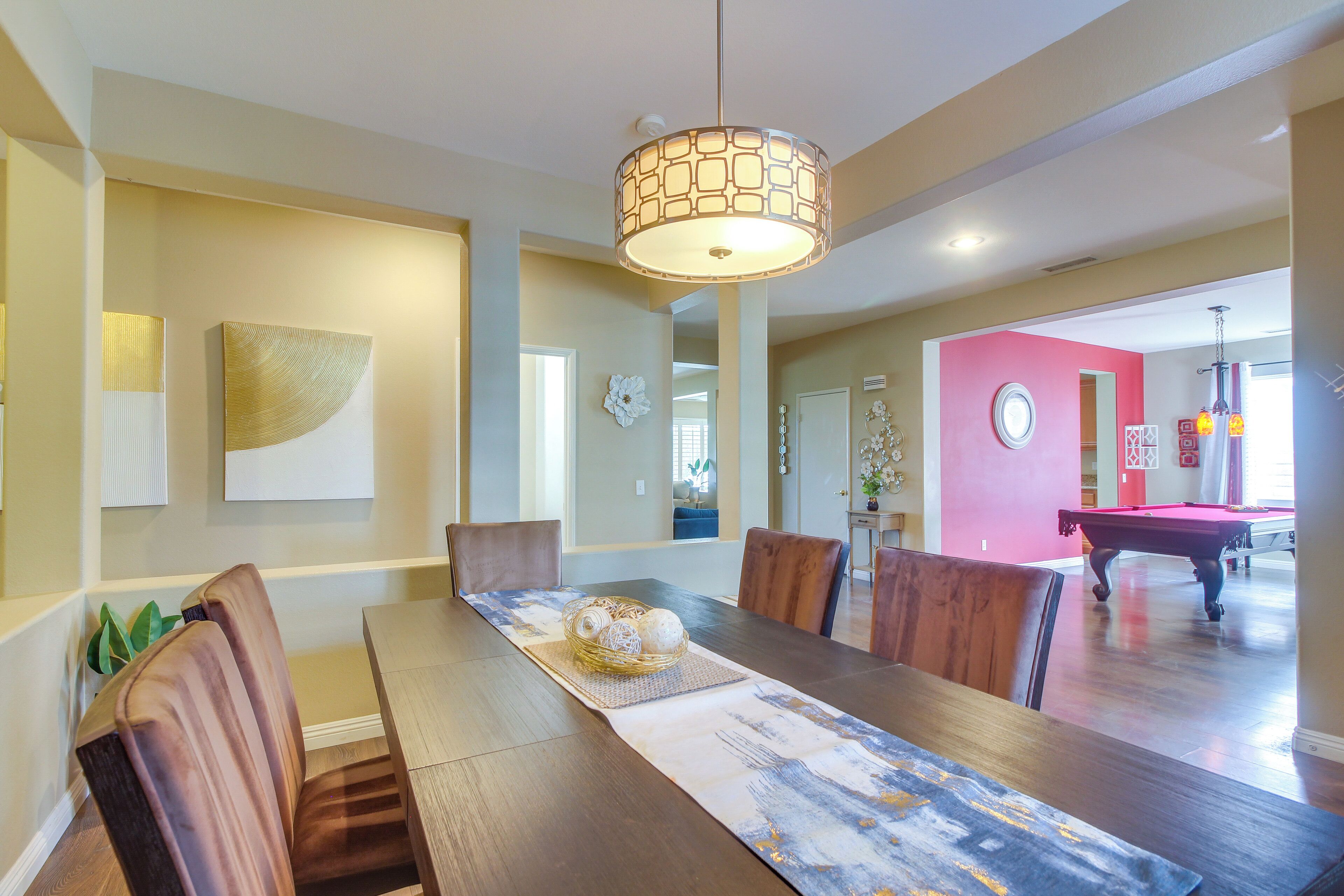 A dining area with a wooden table, chairs, and a hanging light fixture.