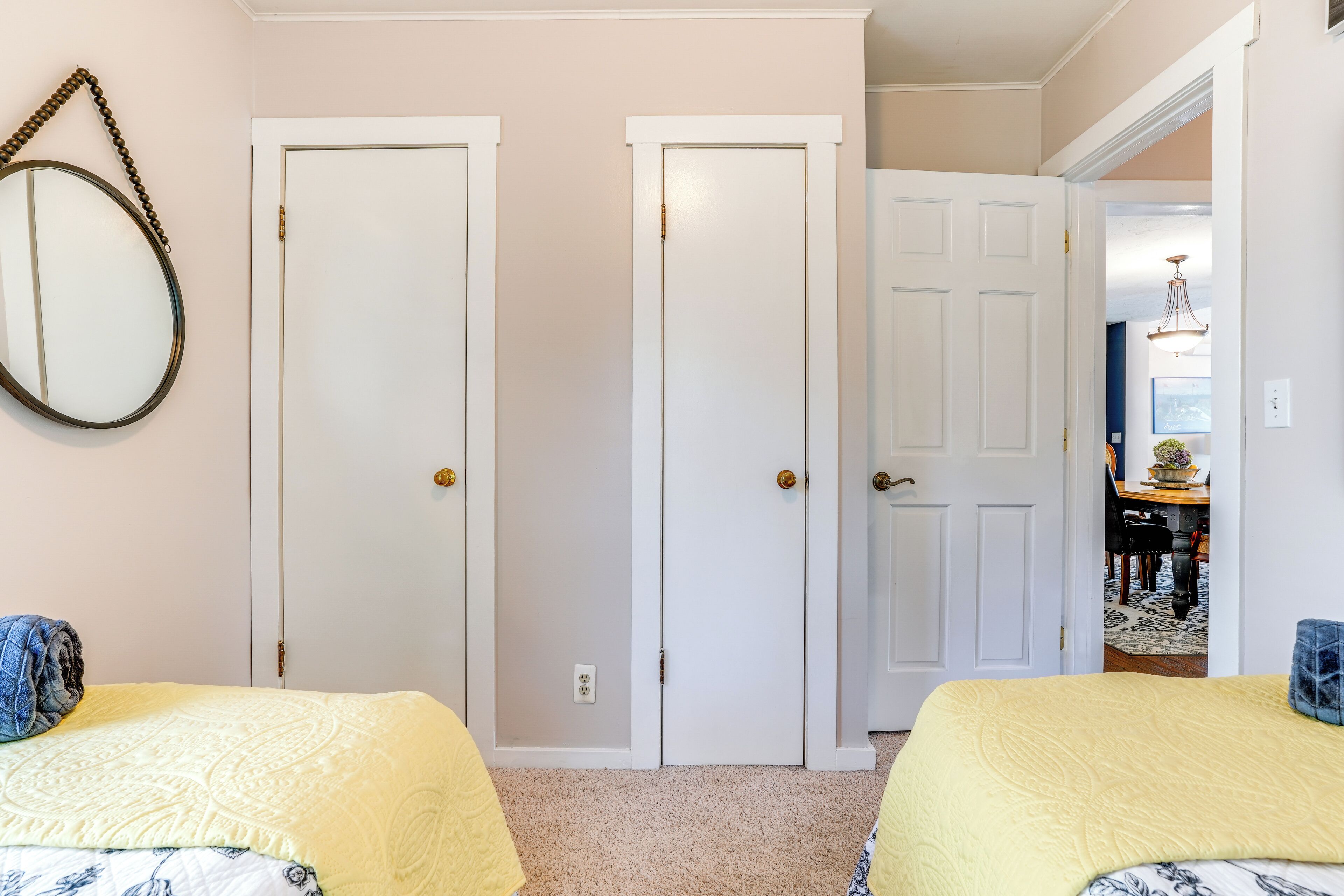 Un dormitorio con dos camas, un espejo y una puerta que da a otra habitación.