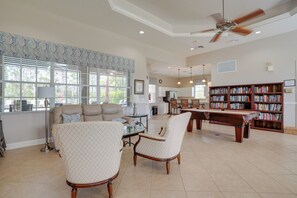 A spacious living room with a large bookshelf, a dining table, and comfortable seating. - Fort Myers Vacation Rental w/ Pool Access! (Fort Myers)