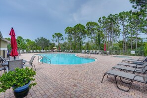 A pool area with lounge chairs and umbrellas, surrounded by trees. - Fort Myers Vacation Rental w/ Pool Access! (Fort Myers)