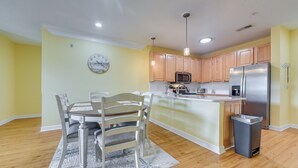 Une cuisine moderne avec des meubles en bois, des appareils électroménagers en acier inoxydable et un coin repas comprenant une table et des chaises.