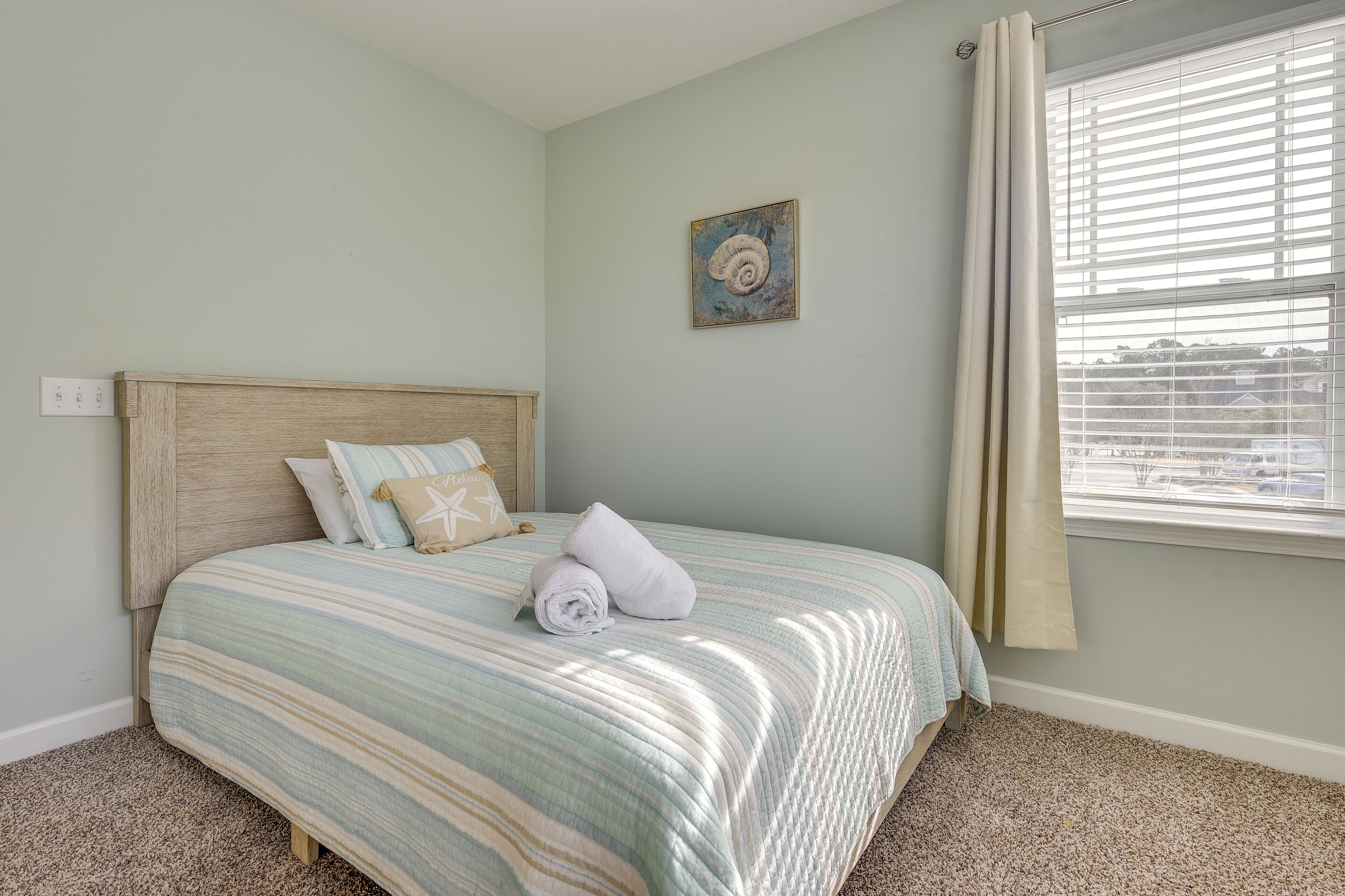 A neatly made bed with a striped bedspread, a headboard, and a pillow with a star pattern.