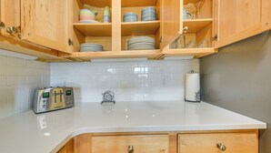 Une cuisine avec des meubles en bois, un plan de travail blanc et un grille-pain Cuisinart.