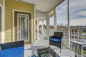 A covered porch with wicker furniture and a view of a parking lot. - Lovely Calabash Condo w/ Balcony, 11 Mi to Beach! (Calabash)