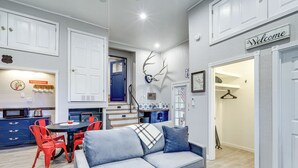Una sala de estar moderna con un sofá gris, sillas rojas y un comedor con mesa y sillas.