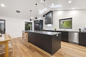 A modern kitchen with a central island, dark cabinetry, and pendant lighting.