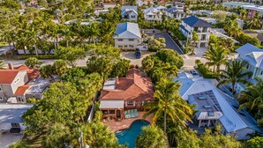 An aerial view of a residential area with houses, a swimming pool, and palm trees.