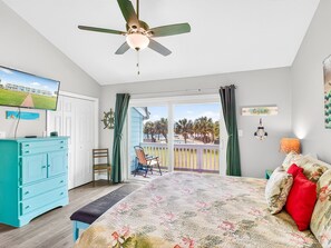 A bedroom with a bed, a ceiling fan, a TV, a dresser, a chair, and a balcony with a view. - Bayfront Kontiki 705 (Rockport)