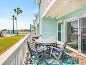 A balcony with a table and chairs, a sliding glass door, and a view of the surrounding area. - Bayfront Kontiki 705 (Rockport)