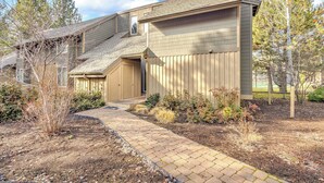 A two-story house with a covered porch, a brick pathway, and a landscaped garden. - Wood fireplace, Wi-Fi access, guest perks, seasonal pool, tennis courts and hot tub access (Sunriver)