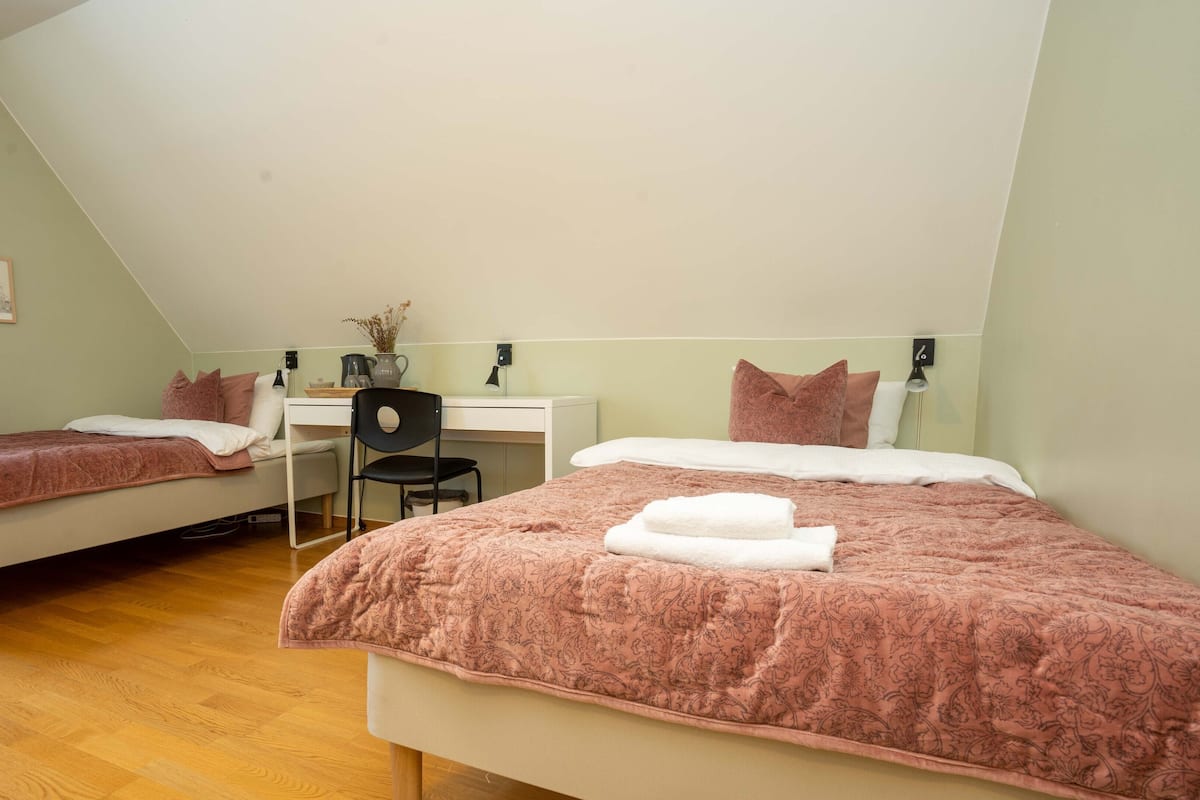 A room with two beds, a desk, and a chair.