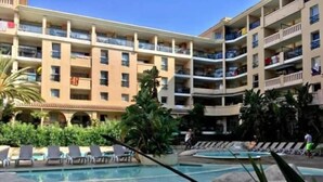 Un hotel con diversi balconi, una piscina e lettini.