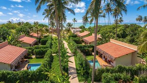 A resort with multiple thatched-roof cottages, a central swimming pool, and lush tropical vegetation. - Monan Boutique Hotel  (Porto de Pedras)