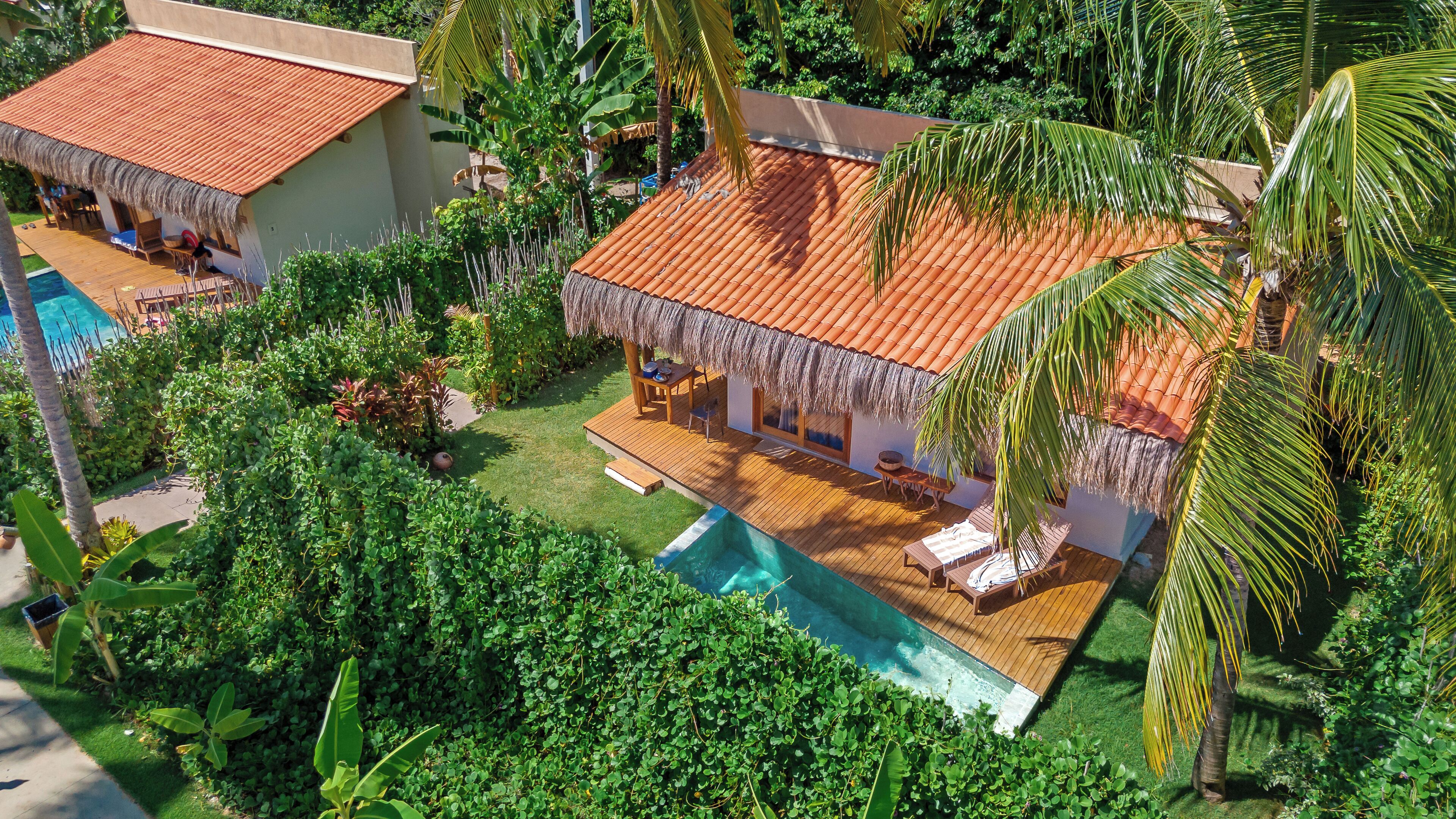 A resort with a pool, thatched-roof structures, and lush greenery.