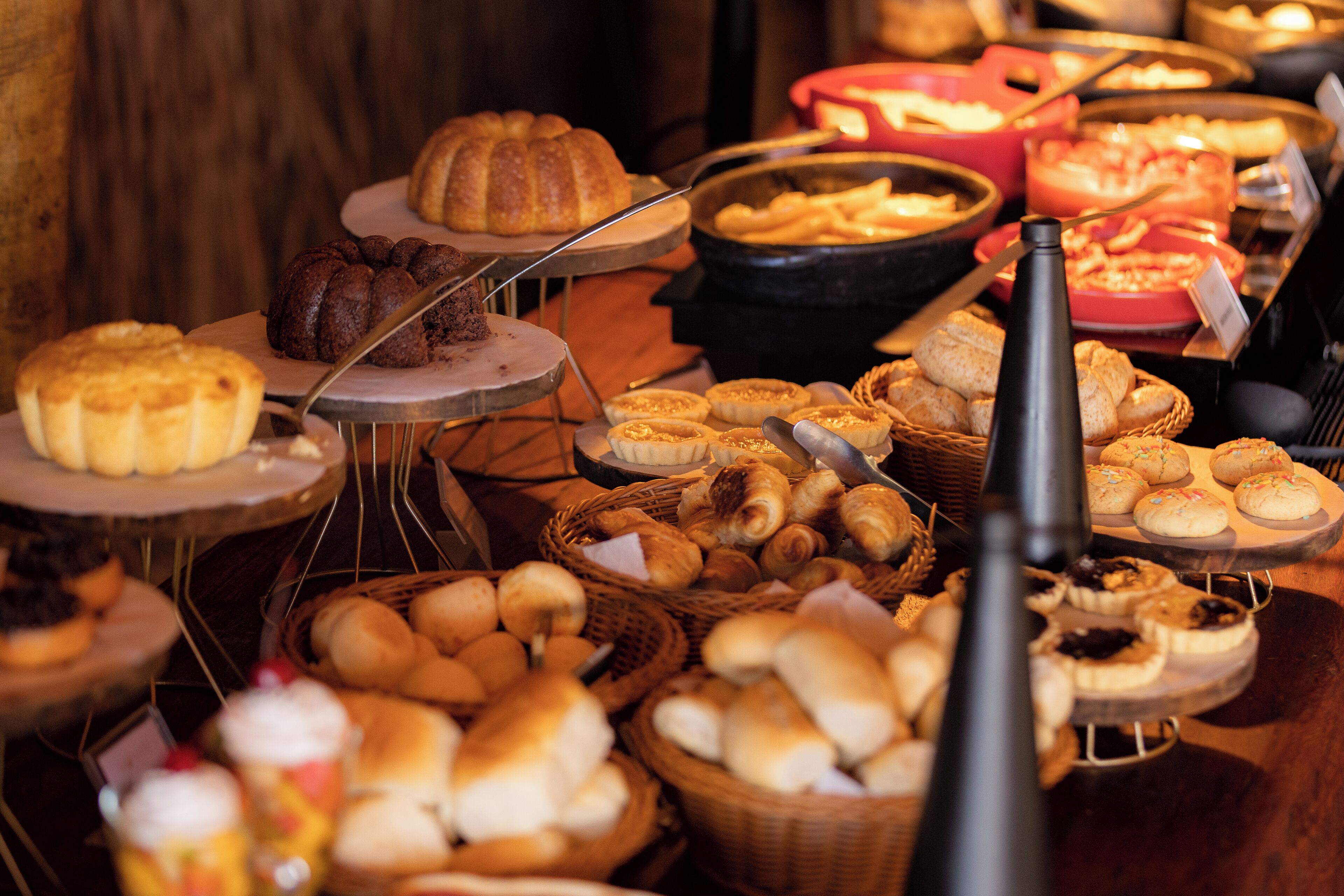 Un bufé con diversas opciones de repostería, incluyendo pasteles, bollos y pan.