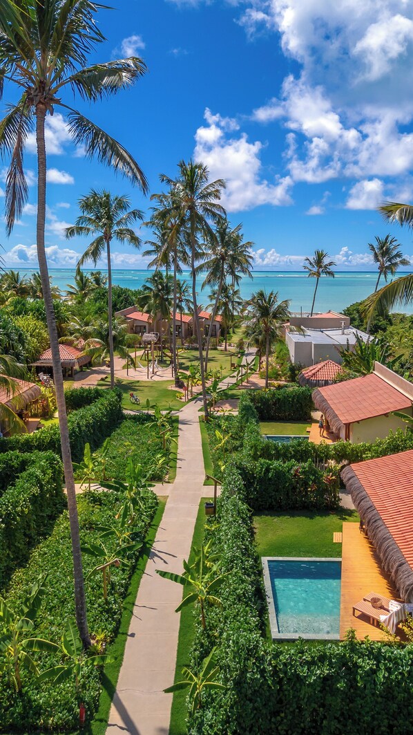 A resort with a pool, palm trees, and a view of the ocean. - Monan Boutique Hotel (Porto de Pedras)