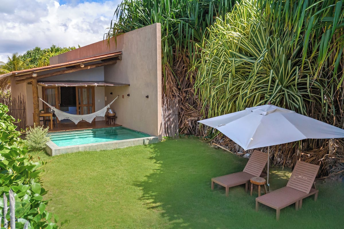 A pool area with a hammock, two lounge chairs, and an umbrella.