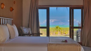 A hotel room with a large bed, a desk, and a view of the ocean. - Monan Boutique Hotel  (Porto de Pedras)